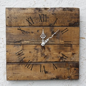 May include: A rustic wooden clock with Roman numeral markings on a brown wooden background. The clock hands are white.