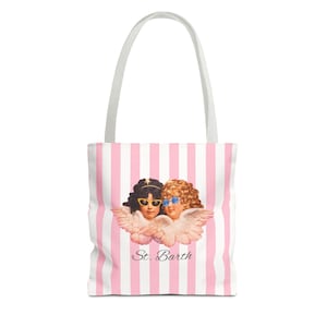 White tote bag with pink vertical stripes and white handles, featuring an illustration of two cherubs wearing sunglasses and the text “St. Barth” printed below them.