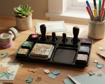 May include: A black ink station with various ink pads, stamps, and a central ink pad area. The words "Distress Oxide" are visible on one of the ink pads. The station is on a wooden surface with craft supplies, including scissors and washi tape.