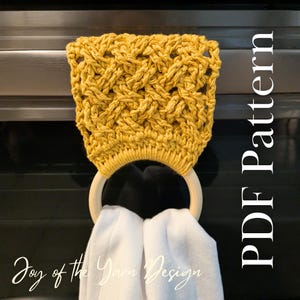 May include: A mustard yellow, crocheted kitchen towel holder with a wooden ring, holding two white towels. The text "PDF Pattern" is vertically aligned on the right side of the image. The words "Joy of the Yarn Design" are written in cursive at the bottom.