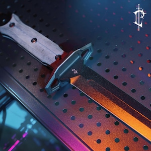 May include: A close-up of a black and silver dagger with a light-colored handle. The blade has an orange gradient. The dagger is on a metal surface with small holes. The logo of a stylized cross is visible on the blade.