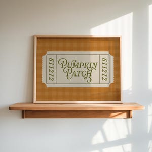 May include: A rectangular framed print featuring a ticket-shaped graphic with the text PUMPKIN PATCH in dark green script and the number 611212 on both sides. The background of the print is an orange and white gingham pattern.