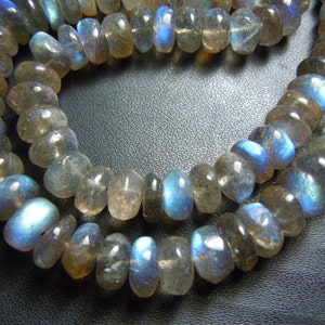 Puede incluir: Cadenas de cuentas de piedras preciosas de labradorita pulida. Las cuentas son una mezcla de gris, marr&oacute;n y azul, con un brillo nacarado. Las cuentas tienen forma ovalada y est&aacute;n ensartadas, adecuadas para la fabricaci&oacute;n de joyas.