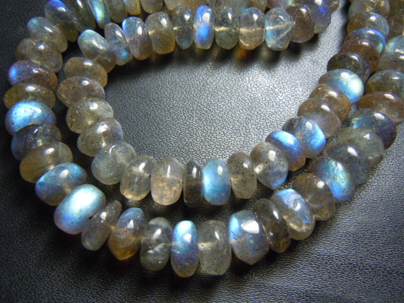 Puede incluir: Cadenas de cuentas de piedras preciosas de labradorita pulida. Las cuentas son una mezcla de gris, marr&oacute;n y azul, con un brillo nacarado. Las cuentas tienen forma ovalada y est&aacute;n ensartadas, adecuadas para la fabricaci&oacute;n de joyas.