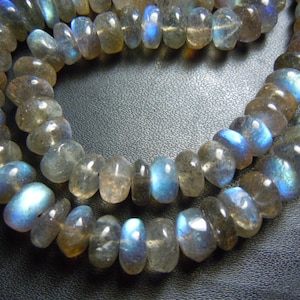 Puede incluir: Hebras de cuentas de piedras preciosas de labradorita pulidas. Las cuentas son una mezcla de gris, marr&oacute;n y azul, con un brillo nacarado. Las cuentas tienen forma ovalada y est&aacute;n ensartadas, creando un collar o una pulsera.