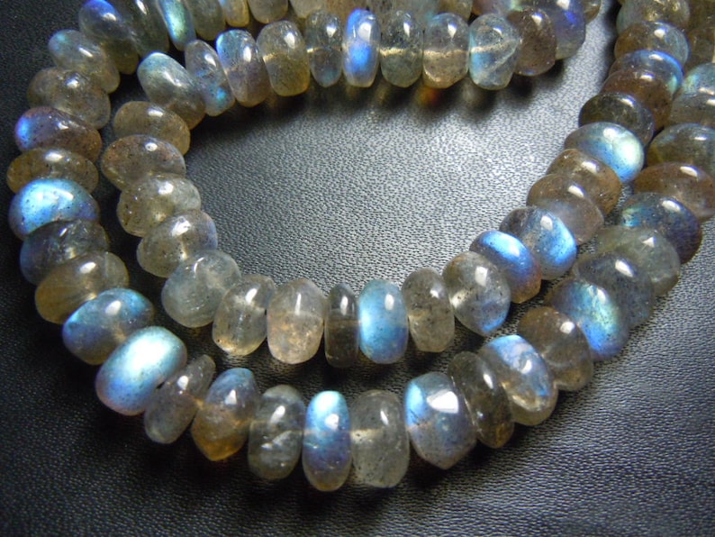 Puede incluir: Hebras de cuentas de piedras preciosas de labradorita pulidas. Las cuentas son una mezcla de gris, marr&oacute;n y azul, con un brillo nacarado. Las cuentas tienen forma ovalada y est&aacute;n ensartadas, creando un collar o una pulsera.