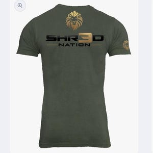 May include: Olive green short-sleeved t-shirt with gold "SHR3D NATION" text and a gold lion head logo. The t-shirt has a crew neck design. The image is of a t-shirt from the brand Shr3d Nation.