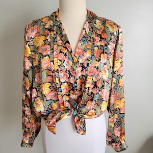 Op de afbeelding: Een blouse met lange mouwen met een paisley- en bloemenprint in tinten roze, geel, turquoise en zwart. De blouse heeft een V-hals en een strik aan de voorkant.