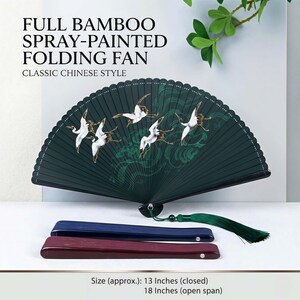 May include: A dark green bamboo folding fan with a crane design, a classic Chinese style. The fan is approximately 33 cm long when closed and 46 cm when open. Includes a green tassel and two wooden fan handles.