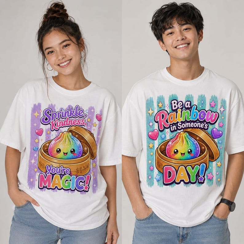 May include: Two white t-shirts featuring a colorful rainbow dumpling in a bamboo steamer. The left shirt displays the text "Sprinkle Kindness, You're MAGIC!" and the right shirt displays the text "Be a Rainbow in Someone's DAY!" with hearts and stars.