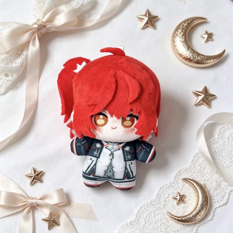 May include: A plush doll with bright red hair and large, expressive eyes. The doll wears a black and white outfit with a detailed design. Gold star and crescent moon decorations surround the doll, along with cream-colored ribbons.