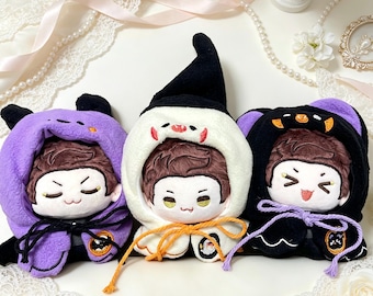 May include: Three plush dolls with brown hair and embroidered facial features, each wearing a different coloured hooded cape. The left doll has a purple hood, the centre doll a white hood with a black pointed hat, and the right doll a black hood.