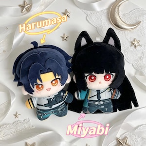Op de afbeelding: Twee pluche poppen, een met donkerblauw haar en de tekst "Harumasa", de andere met zwart haar en de tekst "Miyabi". Beide poppen hebben grote ogen en dragen outfits. De achtergrond bevat linten en stervormige decoraties.