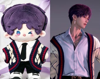 May include: A plush doll with purple hair, dressed in a white shirt, black tie, black trousers, and a navy, red, and white argyle cardigan. The doll is next to a person with purple hair wearing a similar cardigan.