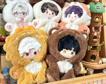 May include: A collection of five plush dolls wearing fuzzy animal-themed hooded onesies with zippers. The dolls feature soft, textured fabric in white, orange, yellow, and brown, with embroidered facial details and paw prints on the sleeves.
