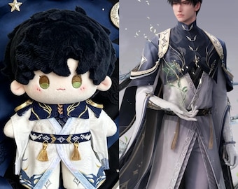 May include: A plush doll with black hair and a white and blue outfit, next to a digital rendering of a person in a similar outfit. The doll has a round head, rosy cheeks, and a detailed costume with gold accents. The digital rendering has a similar color scheme.