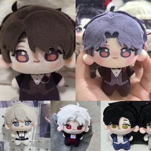 Puede incluir: Una colecci&oacute;n de cinco mu&ntilde;ecos de peluche con personajes de distintos colores de pelo, como marr&oacute;n oscuro, lavanda, blanco y negro. Cada mu&ntilde;eco lleva un esmoquin formal con camisa blanca, chaleco y pajarita, y tiene grandes ojos bordados.