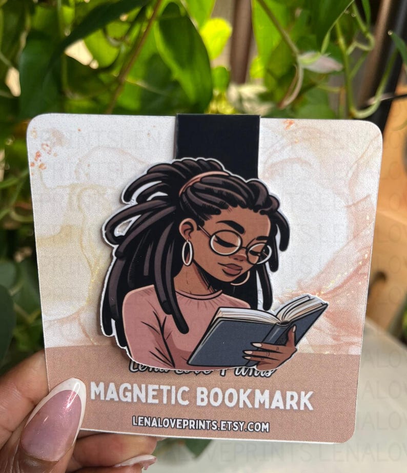 May include: A magnetic bookmark featuring an illustration of a Black woman with locs, wearing glasses, and reading a book. The bookmark has a black magnetic strip and the text "MAGNETIC BOOKMARK" and "LENALOVEPRINTS.ETSY.COM". The background is a watercolor design.