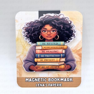 Pode incluir: Marcador de livros magn&eacute;tico com uma ilustra&ccedil;&atilde;o de uma pessoa segurando uma pilha de livros com t&iacute;tulos inspiradores. O marcador de livros tem uma borda marrom com o texto "MAGNETIC BOOKMARK" e "LENA'S PAPERIE". A pessoa tem cabelo encaracolado, &oacute;culos e brincos de argola dourados.