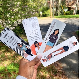 May include: Four rectangular paper bookmarks featuring illustrations of people and text. One has black and white stripes with the text reading is an adventure and a gift you give yourself. Others include phrases like life is more than just black and white, keep being curious, and so many books so little time.