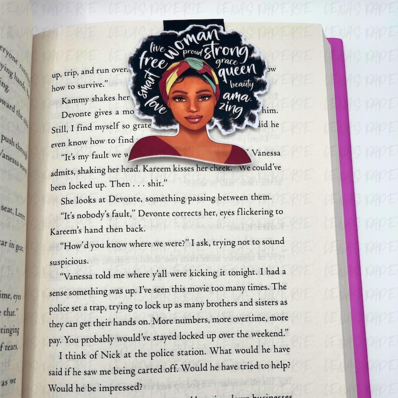 Puede incluir: Un marcap&aacute;ginas con la ilustraci&oacute;n de una mujer con un pa&ntilde;uelo en la cabeza y las palabras "woman, strong, queen, beauty, amazing". El marcap&aacute;ginas est&aacute; en un libro abierto.