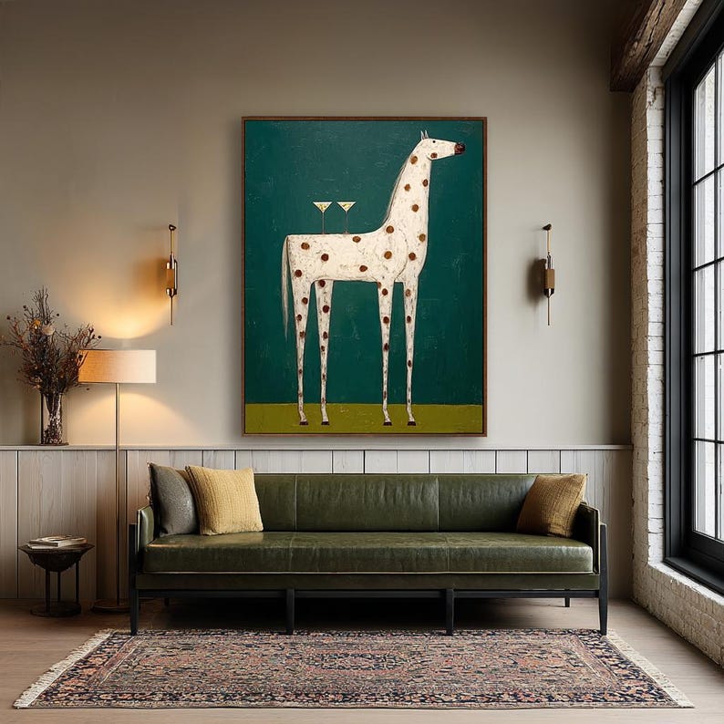 May include: An abstract painting of a white horse with brown spots against a teal background. The horse has long legs and two martini glasses on its back. The painting is framed and hangs above a green leather sofa with yellow pillows.