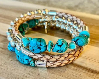 May include: Stacked bracelets featuring turquoise beads, braided leather, and silver accents. The bracelets have a mix of textures and colors, with the turquoise stones adding a pop of bright blue.