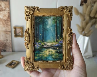 May include: A small rectangular painting in an ornate gold frame featuring a forest scene with a stream, purple flowers, and glowing yellow lights. The artwork depicts a dense woodland path leading into the distance with soft blue and green tones.