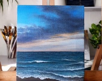 Puede incluir: Pintura original de paisaje marino sobre lienzo. La obra representa un cielo dramático con nubes azul oscuro sobre un océano azul profundo con olas de cresta blanca. El horizonte es visible.