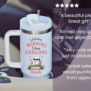 May include: A white insulated tumbler with a handle and a clear straw. The front features a graphic of a mahjong tile character wearing sunglasses, holding a wine glass, with the text: I dont chase WINNING I chase DRAGONS and the name Michelle.