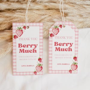 May include: Two rectangular gift tags with a pink and white gingham border, featuring watercolor strawberry illustrations and white daisies. The text reads: THANK YOU Berry Much FOR CELEBRATING MY BIRTHDAY WITH ME! LOVE, ISABELLA. Each tag has a string.