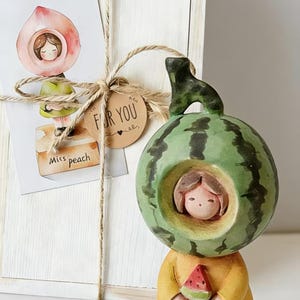 Könnte beinhalten: Eine weiße Keramik-Tasse mit schwarzem Henkel und dem Text "But First, Coffee" in fetter, schwarzer Schrift. Die Tasse steht vor einem neutralen Hintergrund, der ihr schlichtes Design hervorhebt.