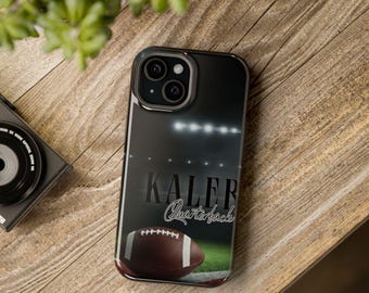 May include: Black phone case featuring a football field design with a football and the text "Kaler Quarterback." The case has a glossy finish and a dark background with stadium lights.