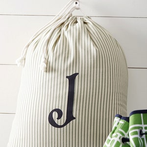 May include: A white and green striped laundry bag with a black letter J on the front.