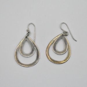 May include: A set of three ceramic mugs with a speckled, matte finish. The mugs are in shades of cream, light gray, and dark gray. Each mug has a simple, minimalist design and a rounded handle. The mugs are stacked on top of each other.