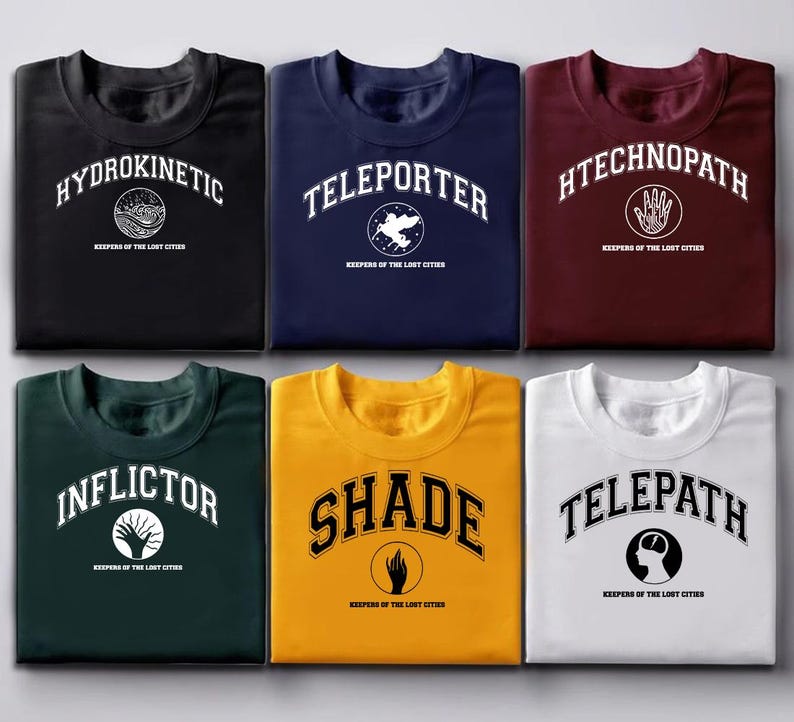 Puede incluir: Seis camisetas de varios colores, cada una con una palabra &uacute;nica en una fuente universitaria: Hydrokinetic, Teleporter, Htechnopath, Inflictor, Shade y Telepath. Cada camiseta tambi&eacute;n tiene el texto "Keepers of the Lost Cities".
