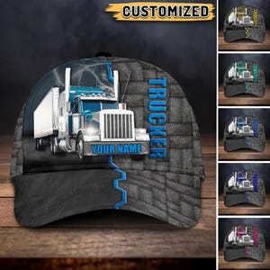 Puede incluir: Gorra de camionero con un diseño de camión semirremolque azul y blanco. La gorra tiene una visera gris y una corona gris con un patrón texturizado. La palabra "TRUCKER" está impresa verticalmente en azul, y el texto "YOUR NAME" está debajo.