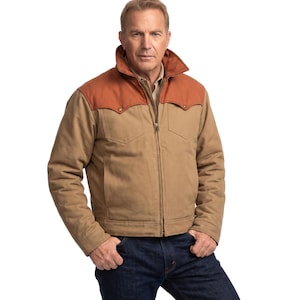 May include: A tan canvas jacket featuring a rust-colored yoke across the shoulders and chest, a high collar, a full-length front zipper, and two chest pockets with snap closures. The jacket is worn over a light-colored shirt and dark blue denim jeans.