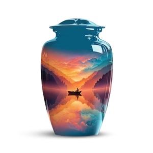 May include: A teal-colored cremation urn with a glossy finish. The urn features a scenic landscape of a lake, mountains, and a sunset. A small boat with a person fishing is in the center of the lake.