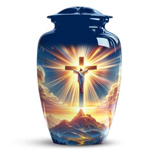 May include: A navy blue cremation urn with a glossy finish. The urn features a vibrant image of Jesus on the cross, radiating light against a sunset backdrop. The design includes mountains and clouds, creating a serene and spiritual aesthetic.