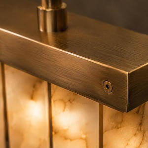 Close up of brushed brass bracket and backlit alabaster panel, creamy veining and warm diffusion