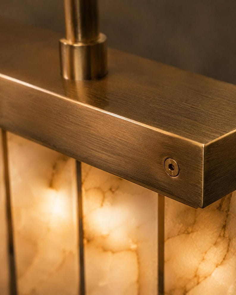 Close up of brushed brass bracket and backlit alabaster panel, creamy veining and warm diffusion
