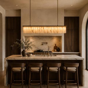 Alabaster linear chandelier over kitchen island, warm glowing stone fins, brushed brass rods