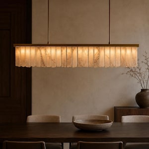 Contemporary stone pendant light hanging over small table, alabaster linear chandelier with warm tone