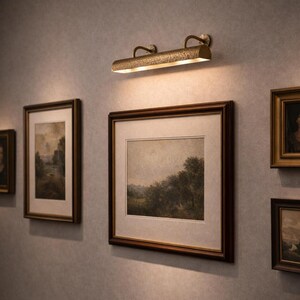 solid brass picture light lighting a gallery wall of framed art, museum art light, antique brass tone