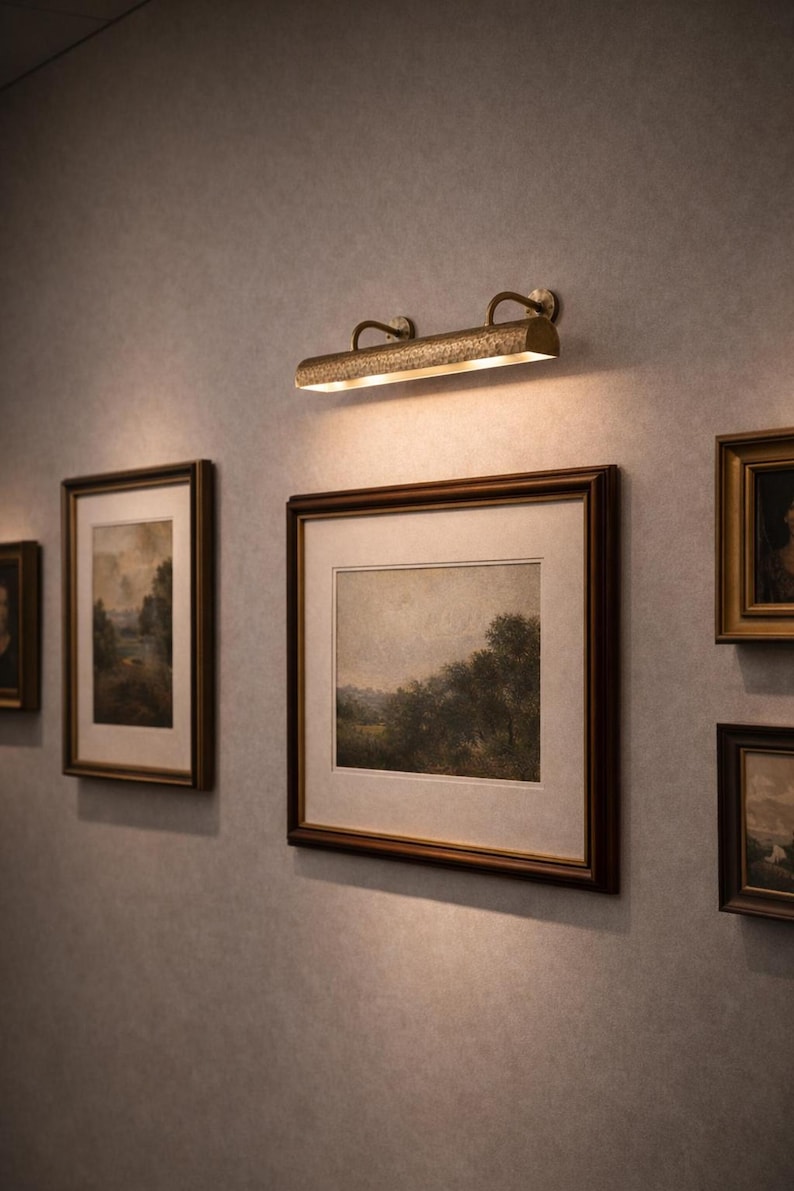solid brass picture light lighting a gallery wall of framed art, museum art light, antique brass tone