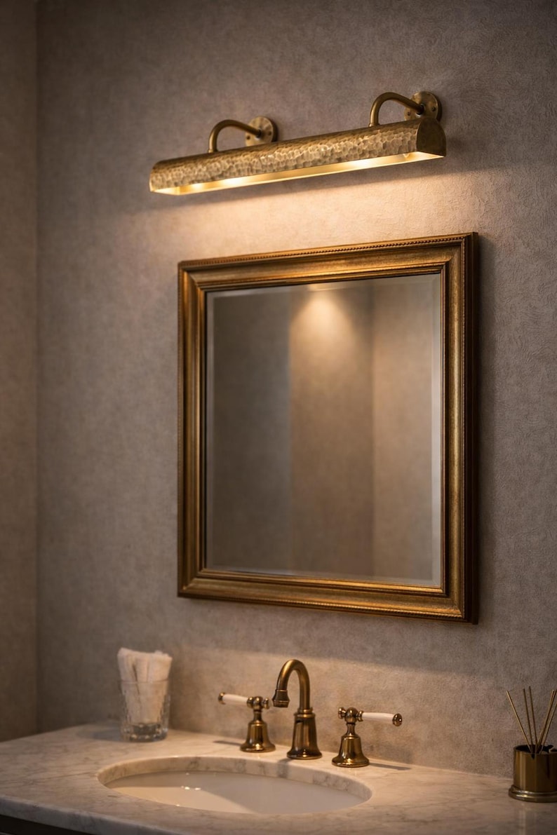 solid brass picture light above a gilded bathroom mirror, mirror picture light, warm luxury finish