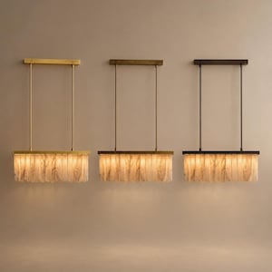Three brass linear chandeliers mounted at staggered drops, alabaster fins glowing softly