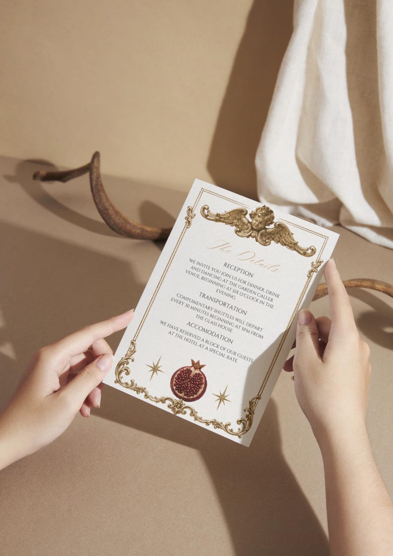 K&ouml;nnte beinhalten: Einladungskarte mit aufwendigen goldenen Details und Text. Die Karte zeigt eine Engel-Illustration oben und eine Granatapfel-Grafik unten. Der Text lautet "The Details" und enth&auml;lt Informationen &uuml;ber Empfang, Transport und Unterkunft.