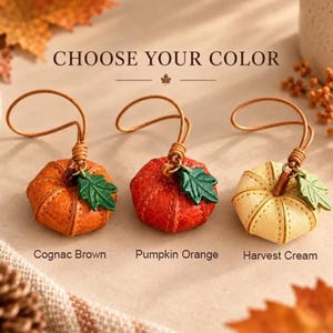 May include: Three pumpkin-shaped leather charms with loops, labeled Cognac Brown, Pumpkin Orange, and Harvest Cream. Each features a green leather leaf accent and visible stitching. The text CHOOSE YOUR COLOR is displayed above the items.